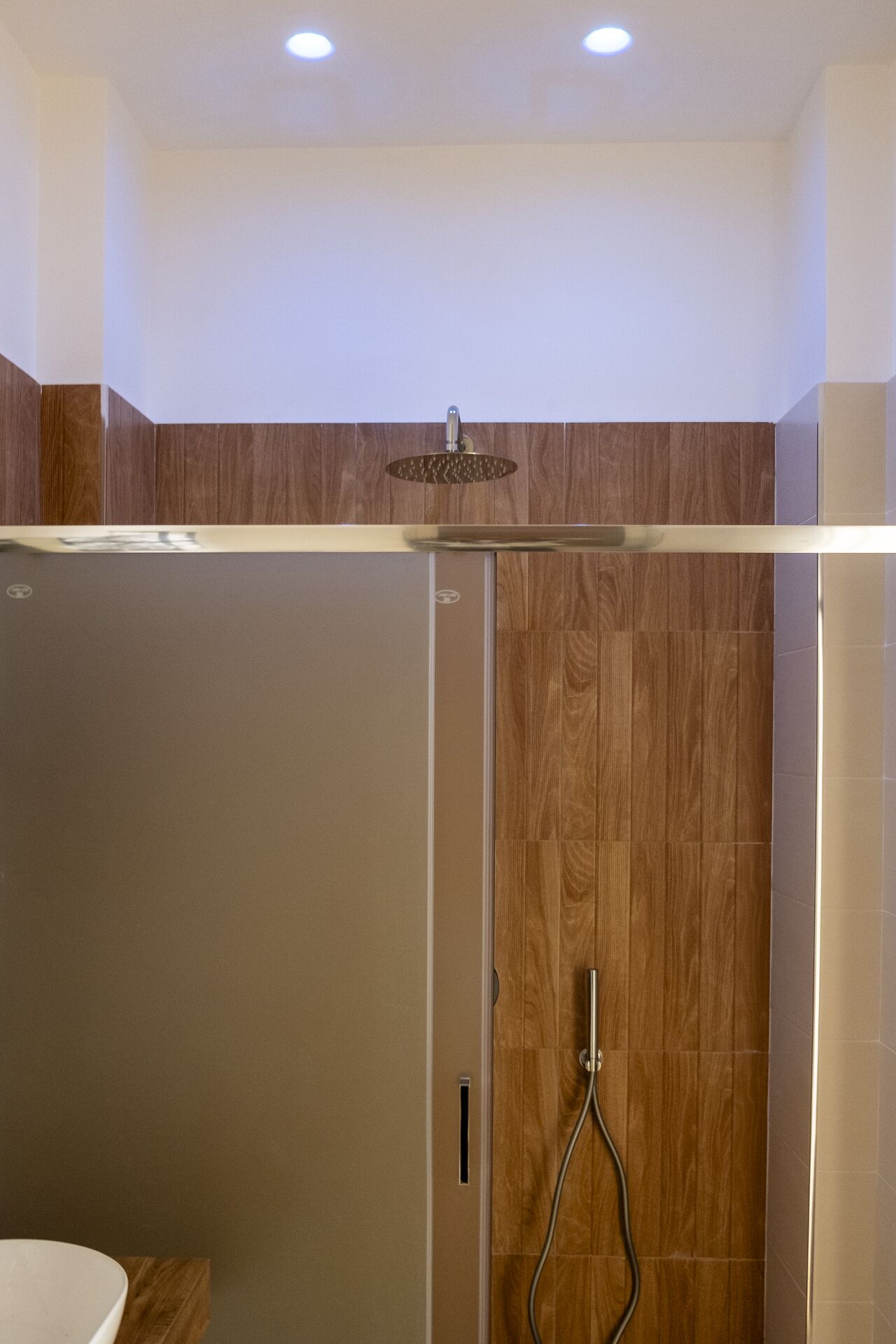 Une salle de bain moderne avec une douche, un lambris en bois et une porte en verre.