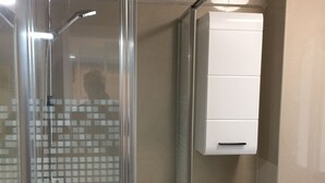 A bathroom with a glass-enclosed shower, a white sink, and a white cabinet. - The Malagueta's Views (Málaga)