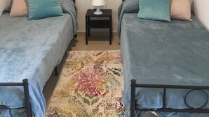 A bedroom with two beds, a nightstand with a lamp, and a beach-themed wall art. - The Malagueta's Views (Málaga)