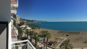 A beach with palm trees, a playground, and a clear blue sky. - The Malagueta's Views (Málaga)