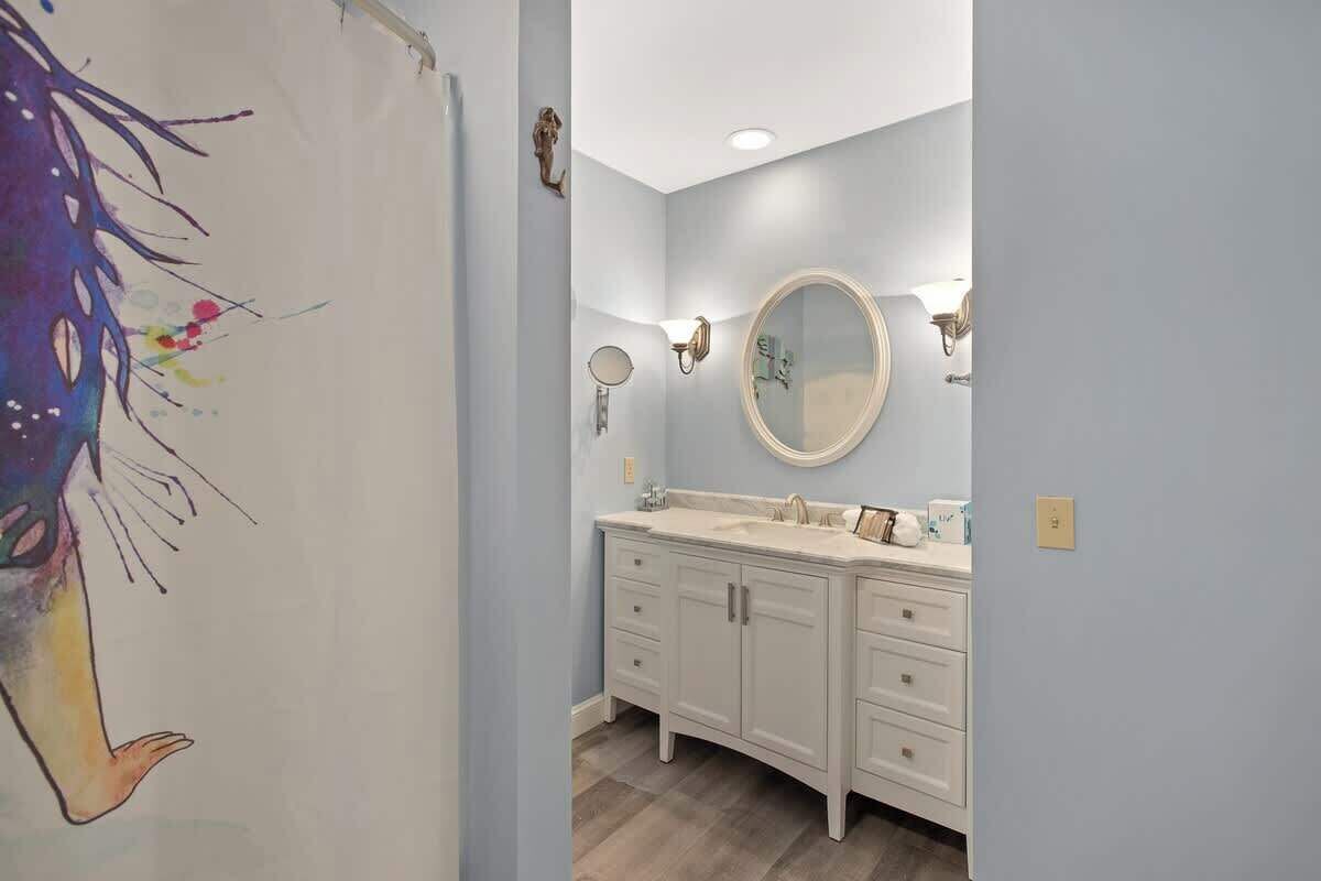 A bathroom with a white vanity, a round mirror, and two wall-mounted lights.
