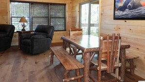 A wooden interior with a dining table, chairs, and a bench.