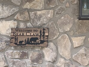 Schild mit Bär und Bäumen, gestaltet an einer Steinmauer.