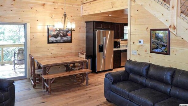 A wooden cabin interior with a dining area, kitchen, and living room.
