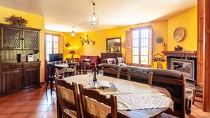 Ein gemütliches Wohnzimmer mit Esstisch, Stühlen, einer Couch und einem Kamin.