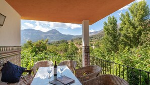 Eine Terrasse mit Korbmöbeln, einem Tisch und einer Weinflasche.