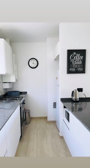 Eine moderne Küche mit weißen Schränken, einem Gasherd und einer Kaffeemaschine auf der Arbeitsfläche.