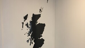 Un escalier avec une rampe et un mur orné d’un motif de carte géographique noire.