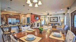 A modern kitchen with a central island, dining area with a wooden table and chairs, and a living room with a sofa and decorative items. - Waveland Family House, 4-Minute Drive to the Beach (Waveland)