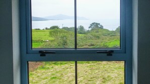 A room with a window overlooking a grassy field and a body of water.