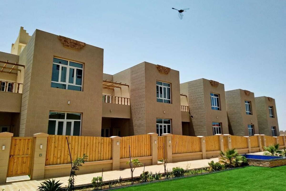 Un edificio moderno de varios pisos con techo plano, ventanas amplias y una cerca de madera alrededor de la propiedad.