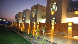 A modern building with multiple floors, large windows, and a well-lit exterior. - Al Asala Resort (Al Hadd)