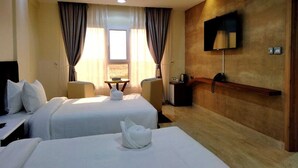 A hotel room with two beds, a TV mounted on the wall, and a small table with a chair. - Al Asala Resort (Al Hadd)