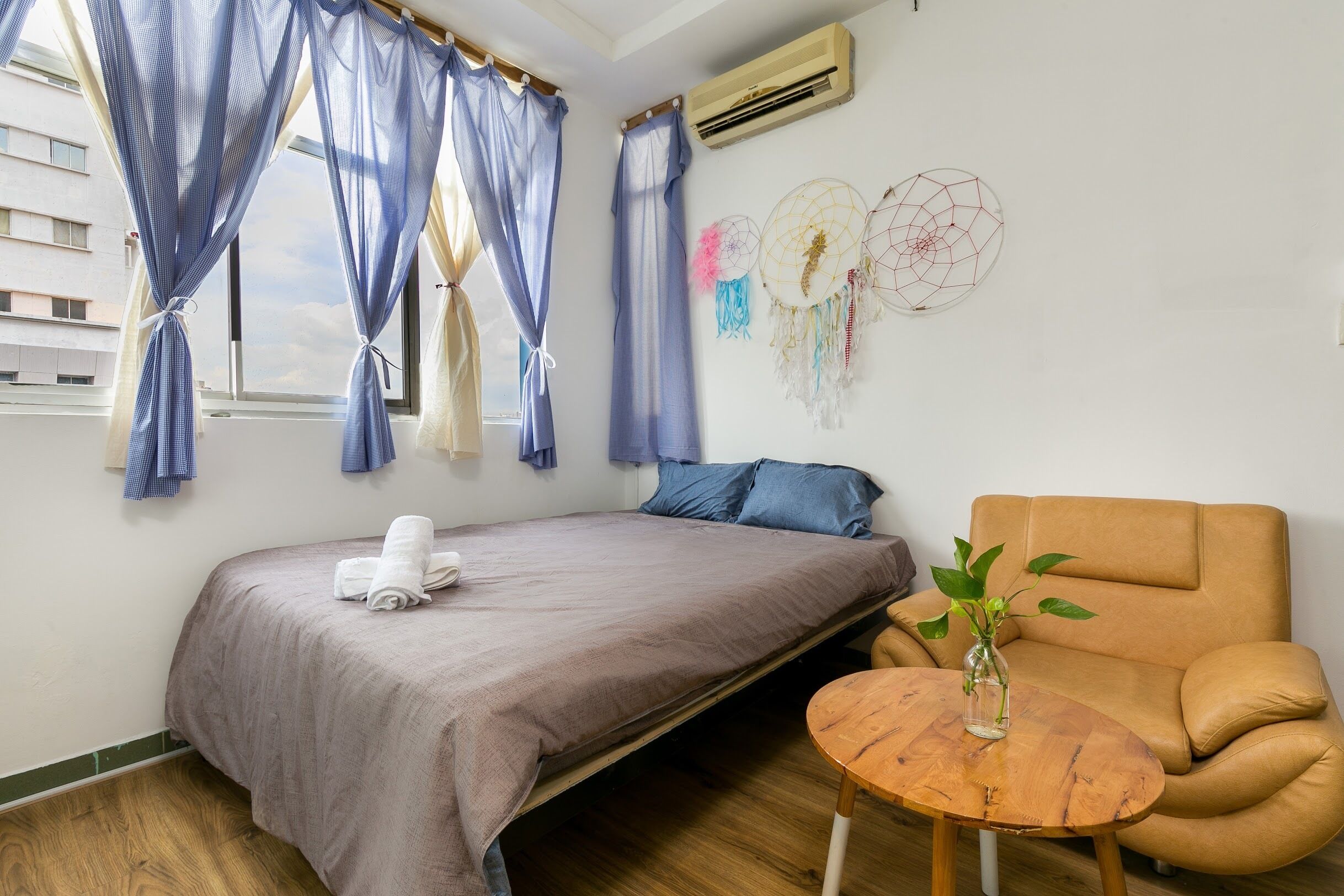 Une pièce comprenant un lit, un canapé, une petite table avec un vase et une fenêtre avec des rideaux.