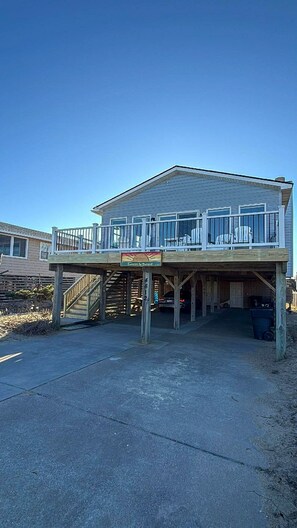 A two-story building with a balcony and a covered area. - Sunrise to Sunset - Steps From the Ocean! Hot Tub! (Kitty Hawk)