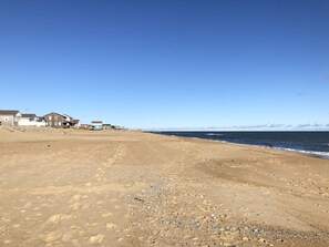A beach with footprints leading to a row of houses. - Sunrise to Sunset - Steps From the Ocean! Hot Tub! (Kitty Hawk)