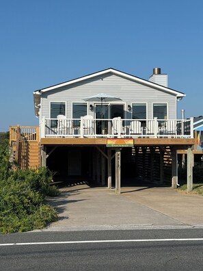 A two-story house with a balcony, a covered entrance, and a wooden deck. - Sunrise to Sunset - Steps From the Ocean! Hot Tub! (Kitty Hawk)