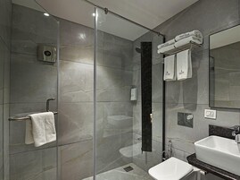 Un baño moderno con cabina de ducha de vidrio, un lavamanos blanco y un perchero para toallas.
