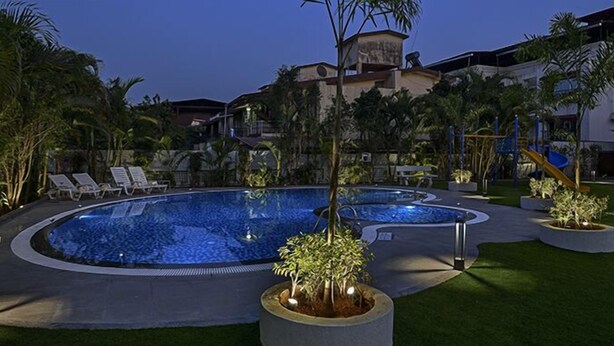 Una piscina de diseño circular, rodeada de palmeras y sillones de descanso.