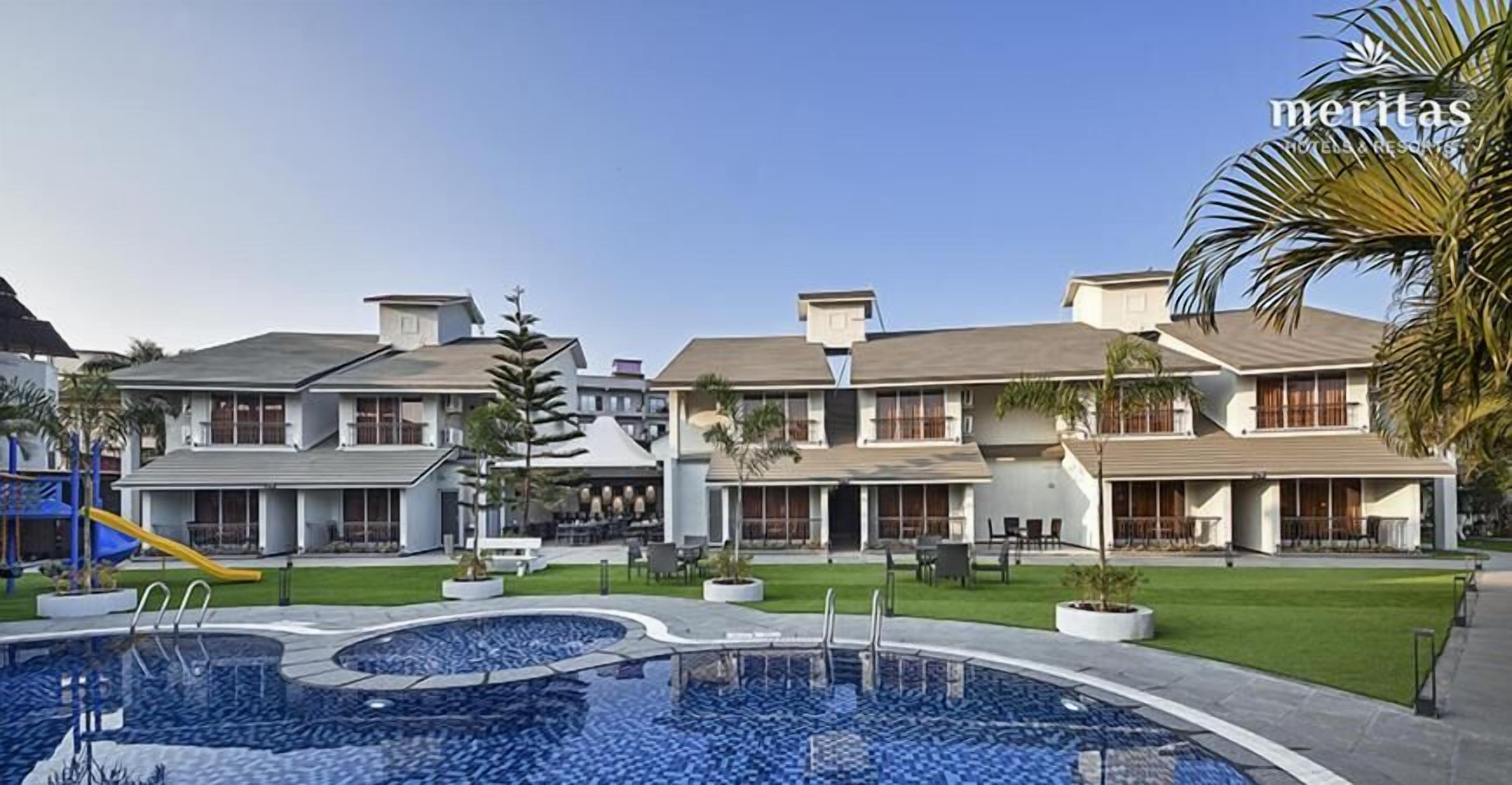 A hotel with a swimming pool, outdoor seating, and a well-maintained lawn.