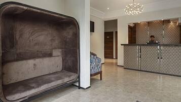 Un hall d’entrée moderne avec un fauteuil suspendu original, un comptoir d’accueil et un mur orné de motifs.
