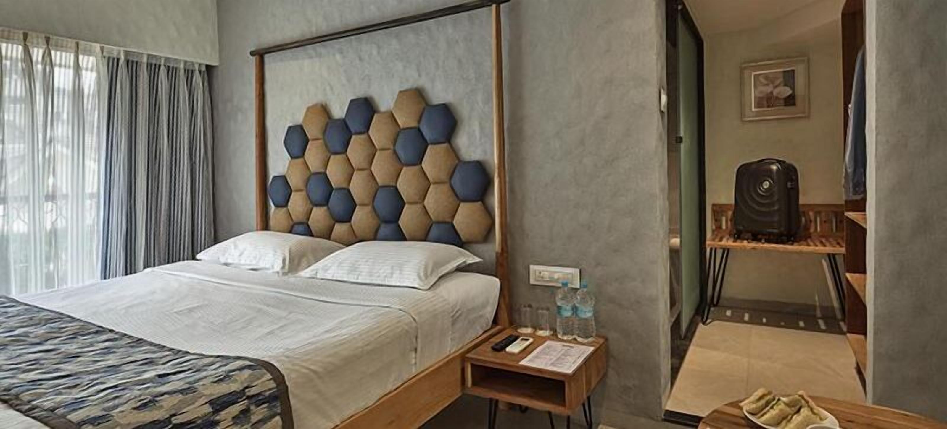 Una habitación de hotel con una cama, una mesita de noche de madera, un escritorio y una silla.