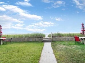 Ein Weg, der zu einem Strand führt, gesäumt von Liegestühlen und Sonnenschirmen.