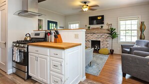 Una cocina con una isla central, una chimenea y un rincón comedor con sofá gris.
