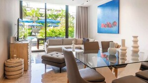 A modern living room with a glass coffee table, sofas, and a dining area.