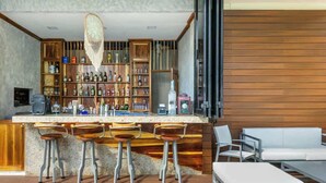 A modern bar area with wooden shelves, bar stools, and a white sofa.