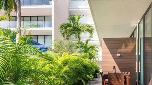 A modern building with a glass facade, outdoor seating area, and lush greenery.