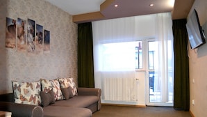 A living room with a sofa, a flat-screen TV, and a large window with curtains. - Alimar (Predeal)