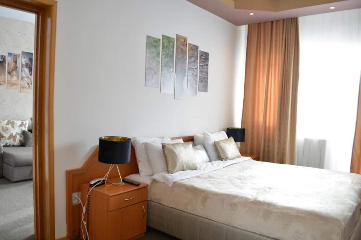 Quarto de hotel com uma cama, mesas de cabeceira, uma escrivaninha e uma cadeira.