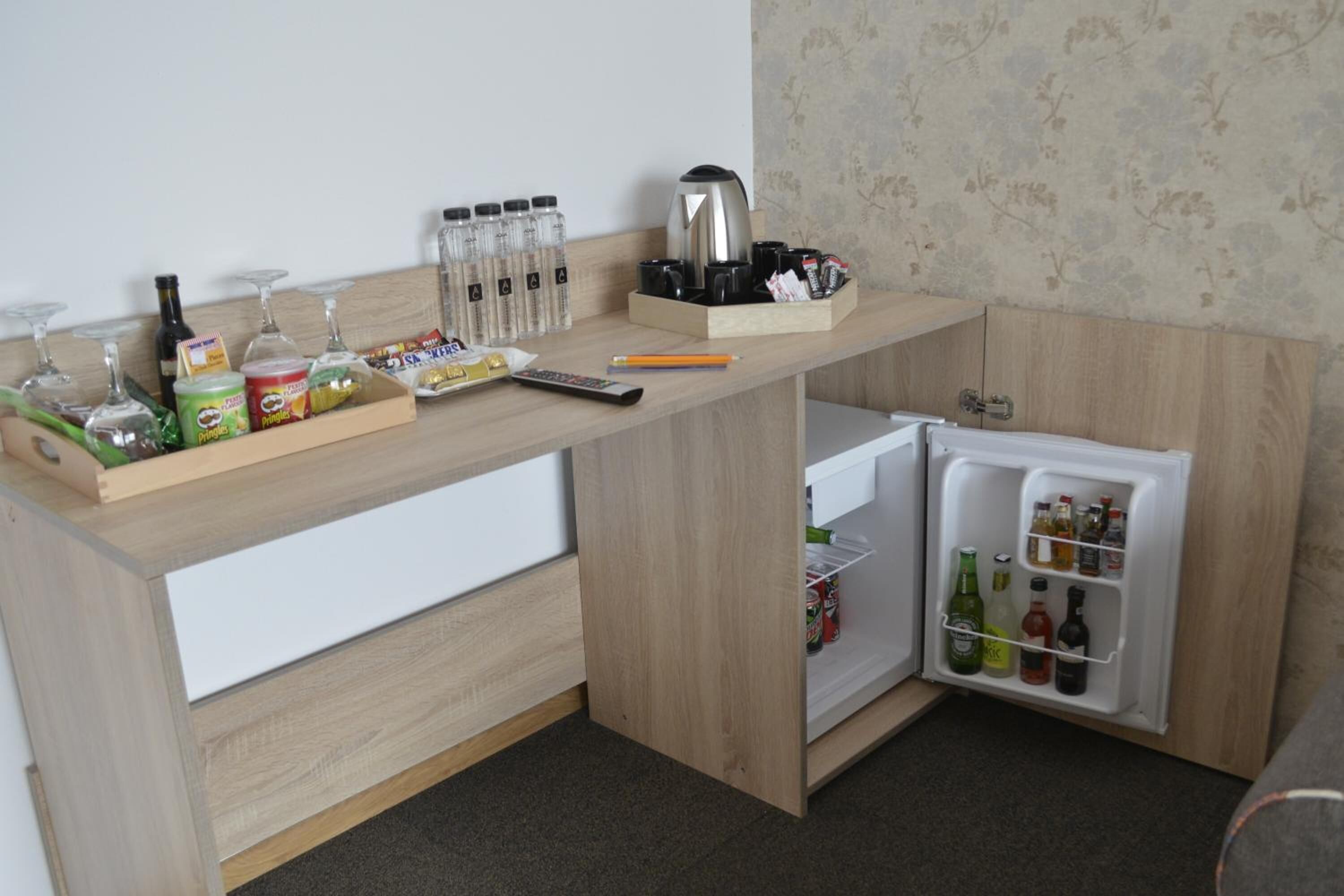 A compact kitchenette with a built-in refrigerator, a coffee maker, and various food items.