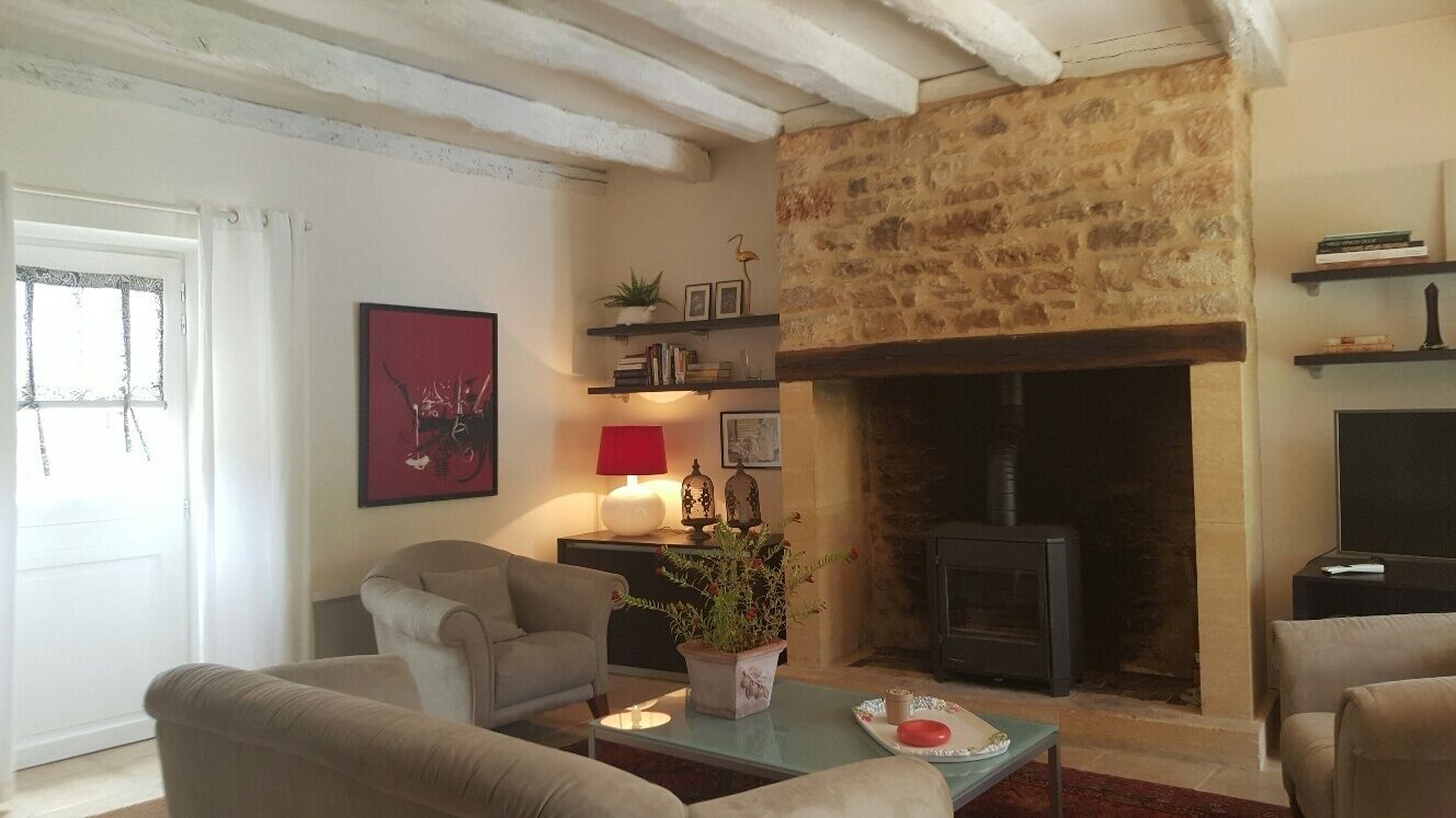 A cozy living room with a stone fireplace, comfortable seating, and a bookshelf.