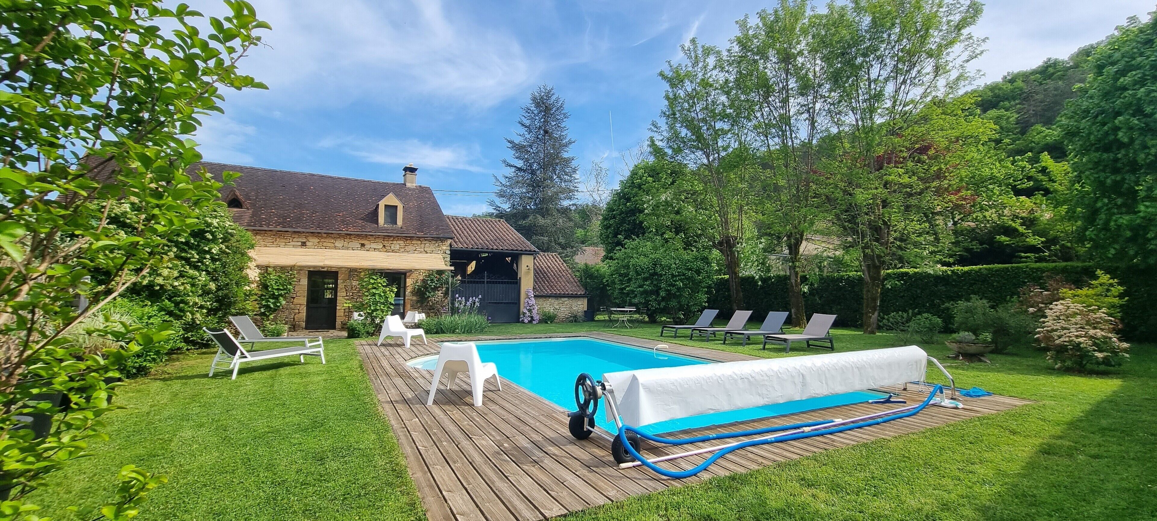 Ein Garten mit Schwimmbad, Liegestühlen und einer Holzterrasse.