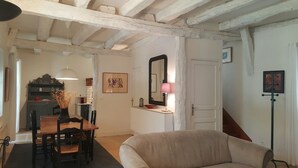 Ett rum med ett matbord i trä, stolar, en soffa, en spegel och en lampa.