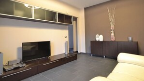 A modern living room with a flat-screen TV, dark wooden entertainment unit, and a beige sofa. - Chicco Apartment Light (Vercelli)