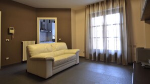A living room with a sofa, a TV, and a window with curtains. - Chicco Apartment Light (Vercelli)