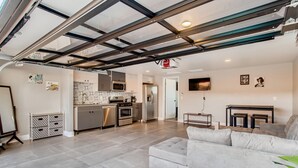A modern kitchen with stainless steel appliances, a dining area with a table and chairs, and a living room with a sofa.