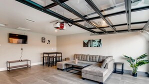 A modern living room with a sectional sofa, a coffee table, a TV, and a ceiling with skylights.