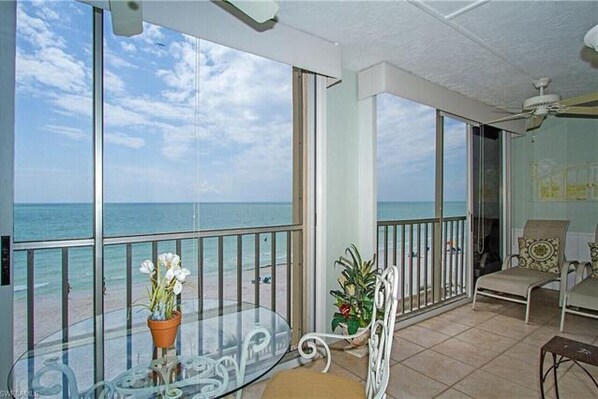 Enjoy the ocean view from this balcony with a glass table and two chairs.