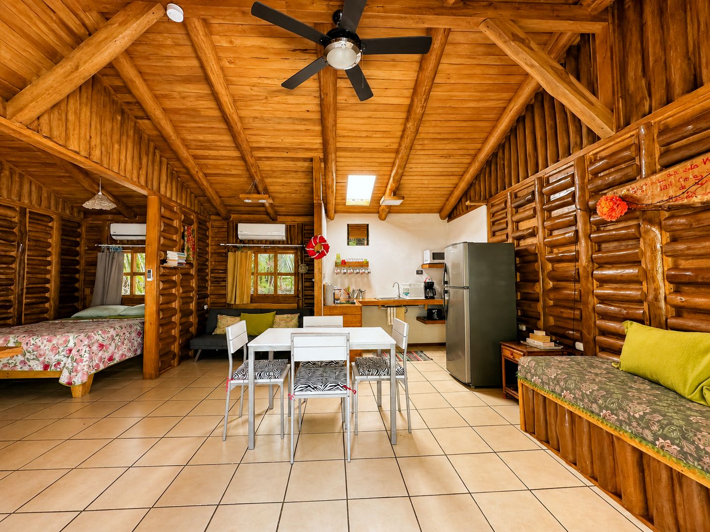 A log cabin interior with a dining area, kitchen, and two bedrooms.