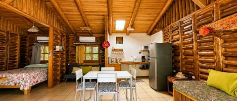 A log cabin interior with a dining area, kitchen, and two bedrooms.