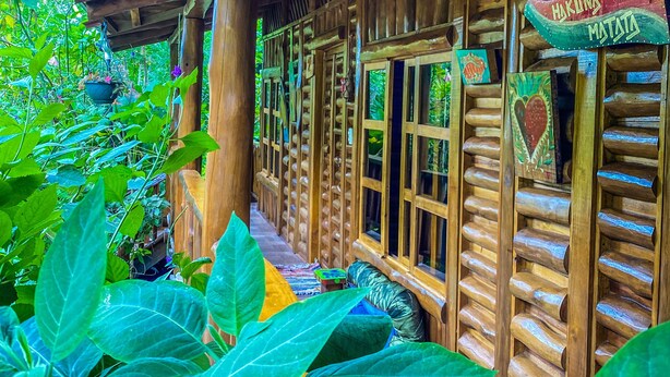 Una cabaña de madera con un porche cubierto, paredes de madera y un letrero que dice "Hakunata Matata".