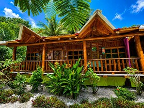 A wooden cabin with a porch, surrounded by tropical vegetation. - Cabañas Lamaite (Sámara)