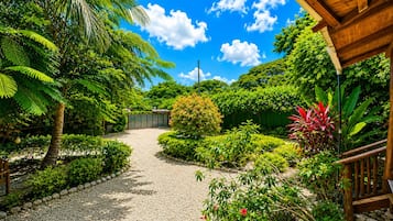 Un sendero de jardín que conduce a un edificio con terraza de madera y zona cubierta.