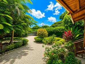 A garden pathway leading to a building with a wooden deck and a covered area. - Cabañas Lamaite (Sámara)
