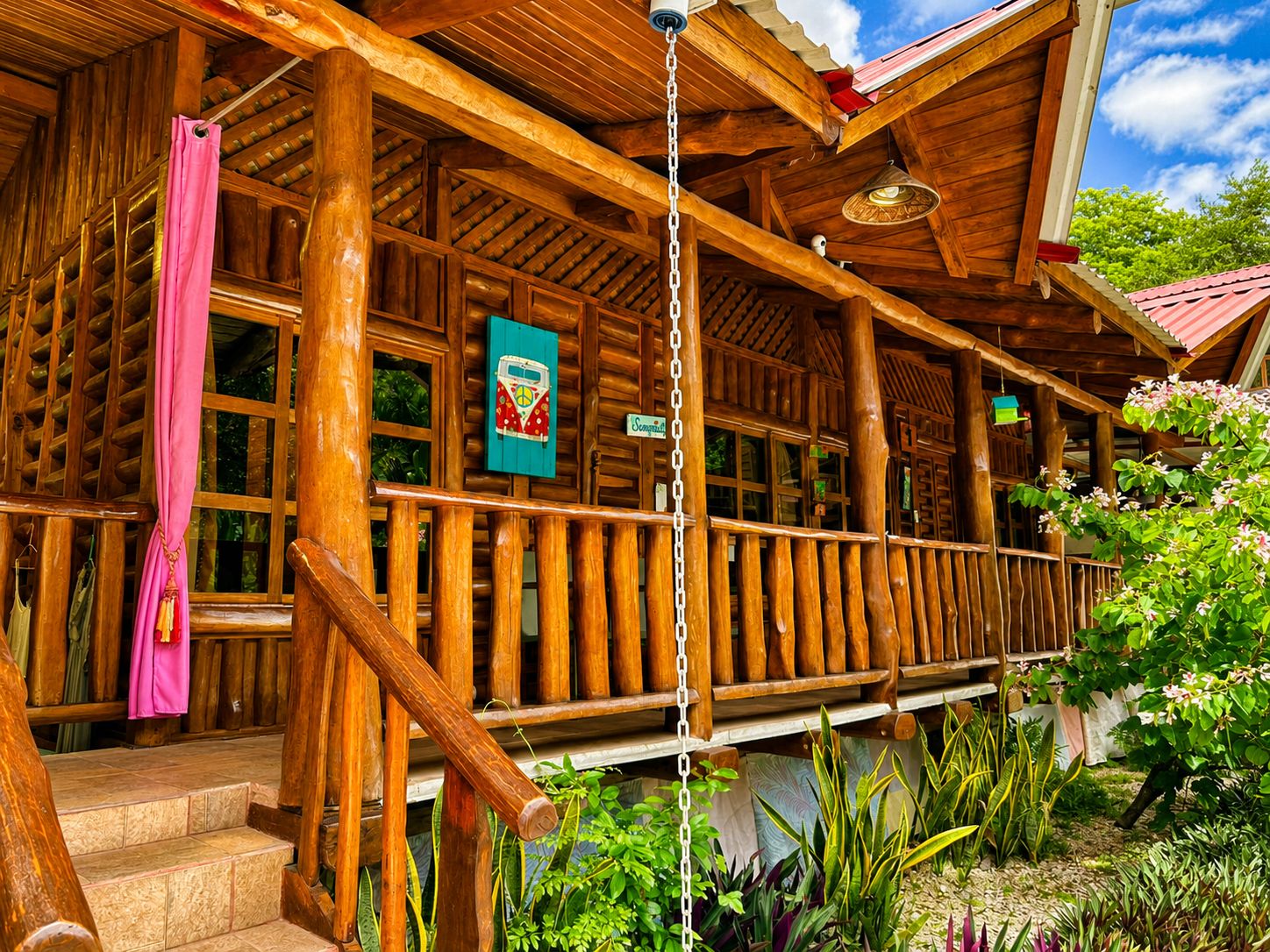 Eine Holzhütte mit einer Veranda, Stufen, die zum Eingang führen, und einer hängenden Leuchte.