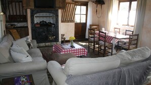 A cozy living room with a fireplace, a dining table with chairs, and a sofa. - Castle Combe - the prettiest Cotswold village near Bath / 6 bedrooms ensuite (Castle Combe)